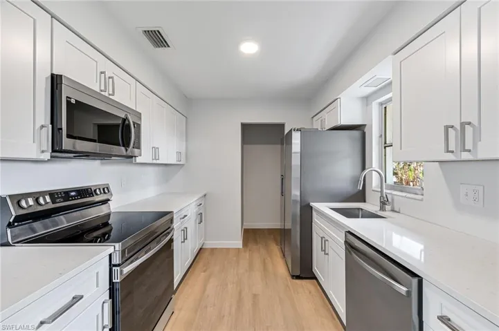 Kitchen featuring white cabinetry, stainless steel appliances, sink, and light hardwood / wood-style floors