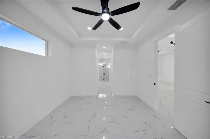 Empty room with recessed lighting, a raised ceiling, and ceiling fan
