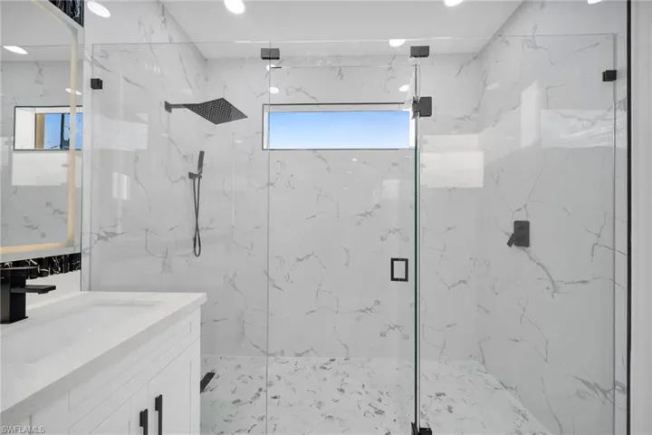 Full bathroom with a marble finish shower, vanity, stone wall, and recessed lighting