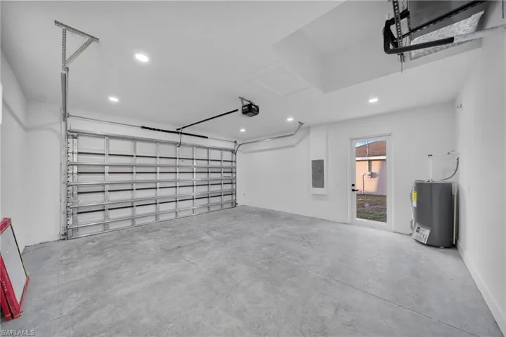 Garage featuring electric water heater, recessed lighting, electric panel, and a garage door opener