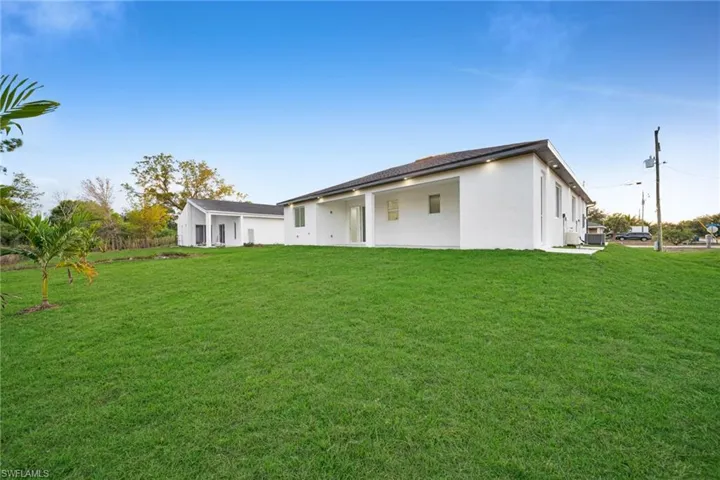 Back of property featuring stucco siding, a lawn, and a patio area
