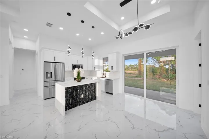 Kitchen with a kitchen island, appliances with stainless steel finishes, hanging light fixtures, white cabinets, and recessed lighting