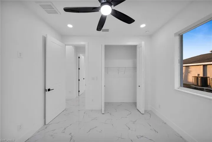 Unfurnished bedroom with light marble finish floors, a ceiling fan, a closet, and recessed lighting