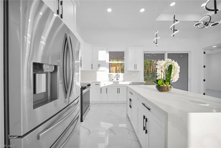 Kitchen featuring appliances with stainless steel finishes, white cabinets, light stone countertops, recessed lighting, and a kitchen island