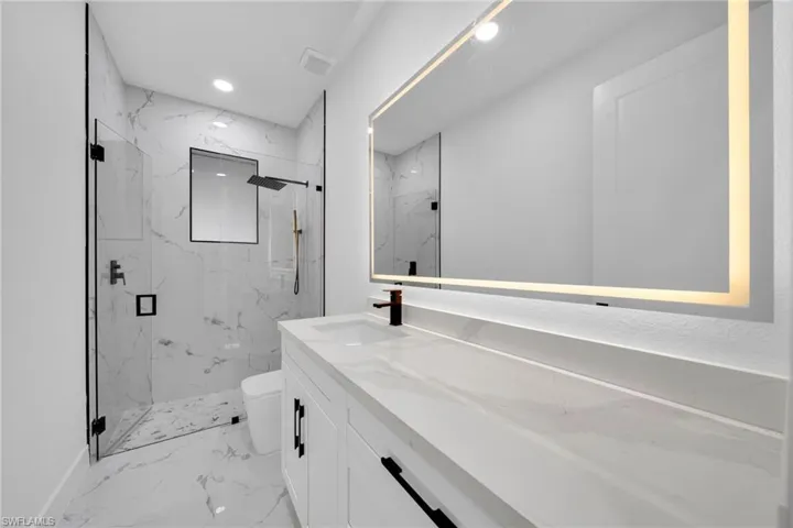 Full bath with a marble finish shower, vanity, recessed lighting, and light marble finish flooring