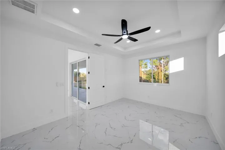 Unfurnished room with recessed lighting, light marble finish flooring, a ceiling fan, and a raised ceiling