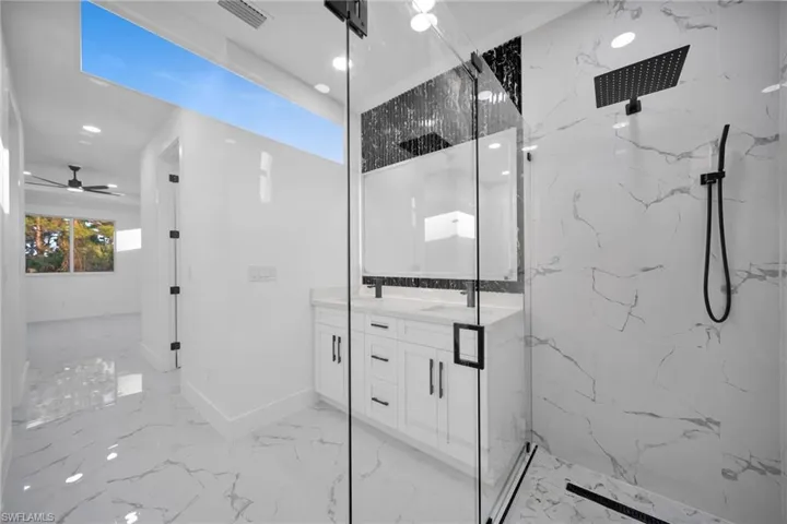 Full bathroom featuring double vanity, a marble finish shower, recessed lighting, ceiling fan, and light marble finish floors