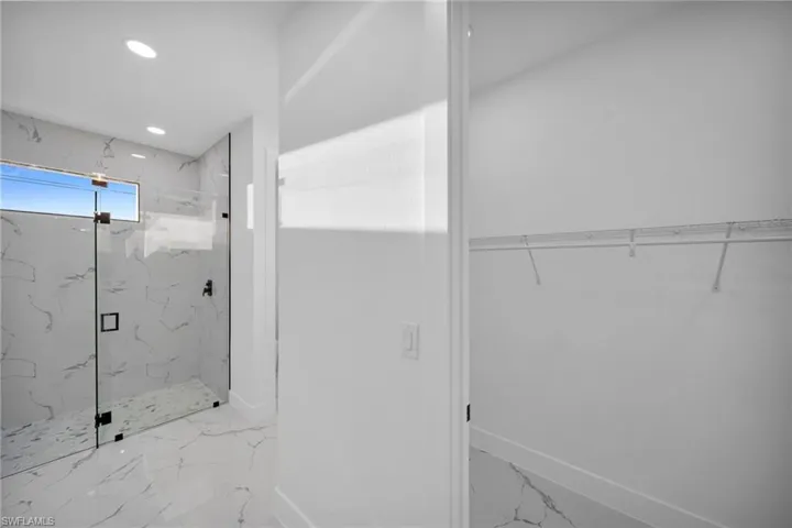 Full bathroom with a walk in closet, a marble finish shower, recessed lighting, and light marble finish flooring