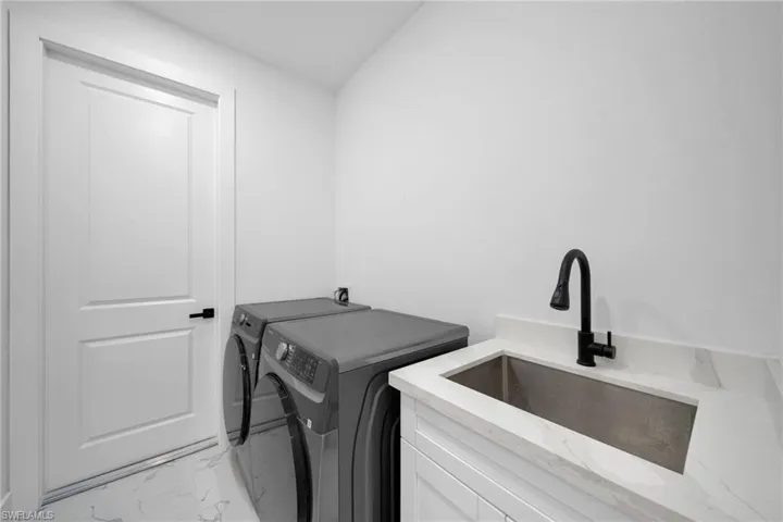 Laundry room featuring washer and dryer and light marble finish floors
