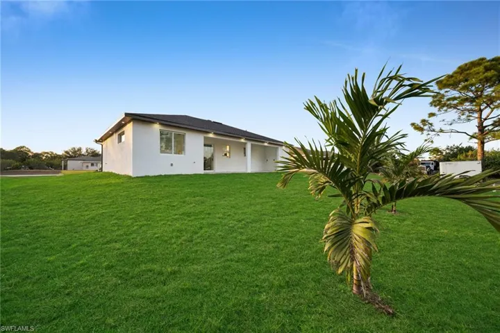 Back of house with a yard, stucco siding, and a patio area