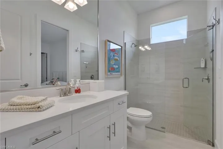 Modern bathroom featuring a single vanity with shaker-style cabinetry, a solid surface countertop, and a rectangular sink