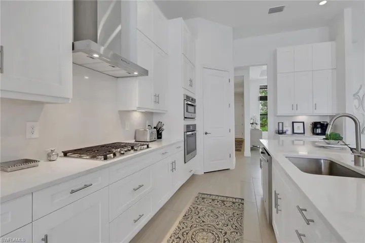 Modern kitchen featuring extensive white cabinetry, light-toned countertops, and tile flooring