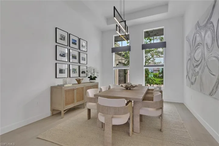 Tall windows with integrated blinds, a linear ceiling light fixture, and light-toned wood-finish flooring