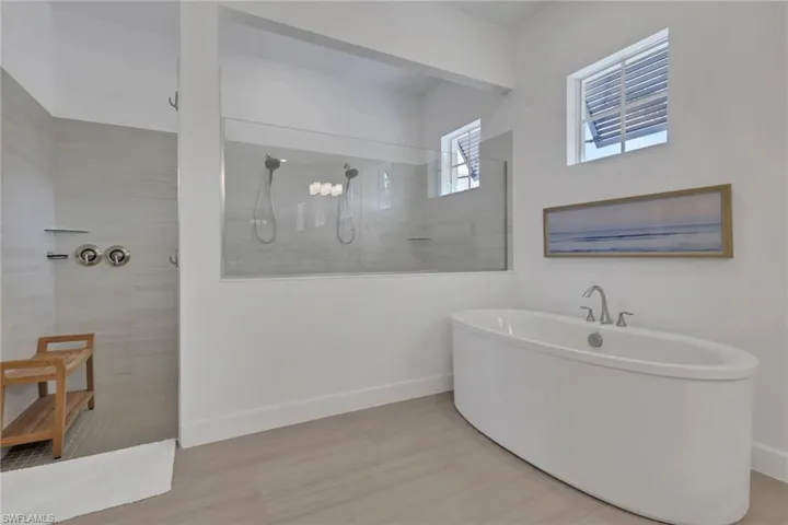 Freestanding soaking tub with a deck-mounted faucet and an expansive walk-in shower featuring a glass enclosure