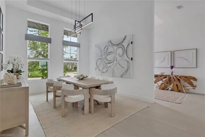 Dining area featuring tall windows, contemporary linear pendant lighting, high ceilings, and light wood-finish flooring
