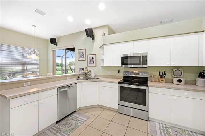 Kitchen with decorative light fixtures, white cabinets, sink, appliances with stainless steel finishes, and light tile patterned floors