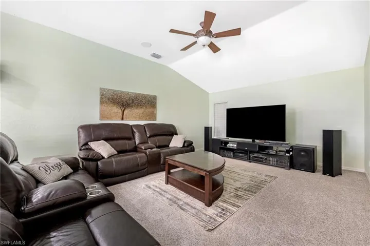 Living room with carpet flooring, ceiling fan, and vaulted ceiling