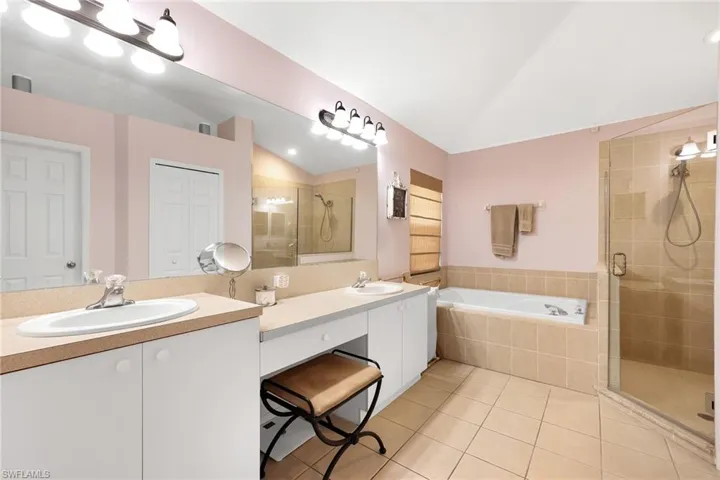 Bathroom featuring tile patterned floors, double sink vanity, plus walk in shower, and vaulted ceiling
