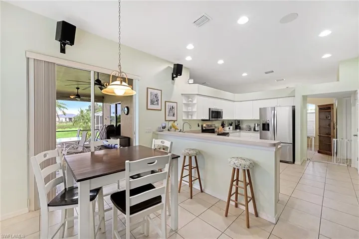 Kitchen featuring kitchen peninsula, light tile patterned floors, white cabinets, and stainless steel appliances