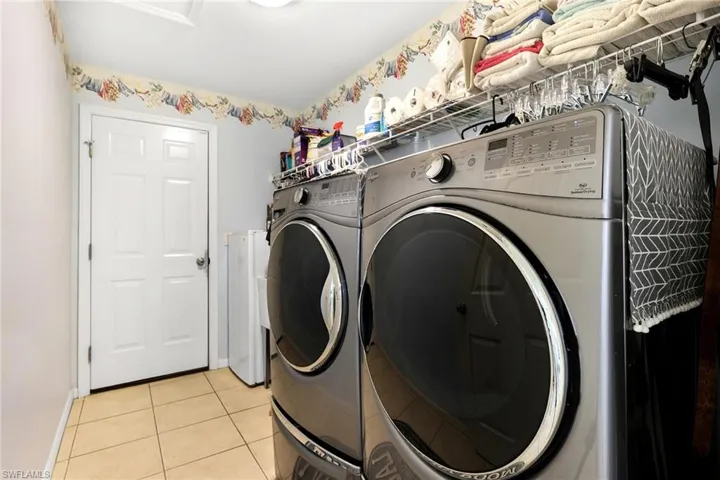 Clothes washing area with independent washer and dryer and light tile patterned floors