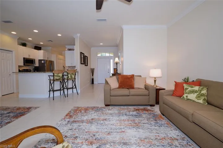 Living area featuring light tile patterned flooring, ornamental molding, ceiling fan, and recessed lighting
