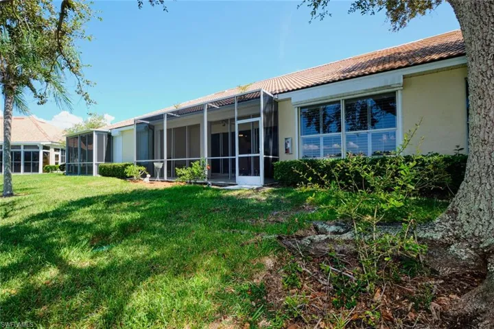 Back of property with stucco siding, a tiled roof, a sunroom, and a yard