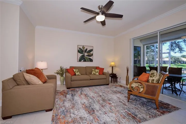 Living area with ceiling fan, crown molding, and light tile patterned floors