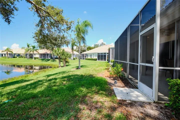 View of green lawn featuring a sunroom, glass enclosure, and a water view