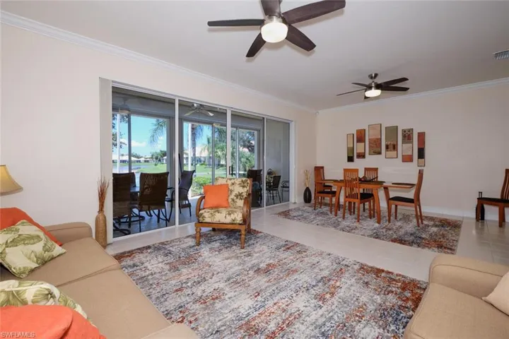 Living area with crown molding, tile patterned flooring, and a ceiling fan