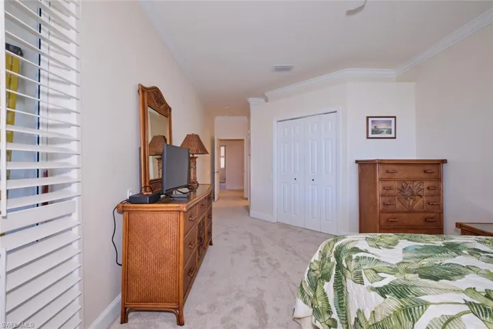 Bedroom featuring ornamental molding, carpet, a closet, and a ceiling fan