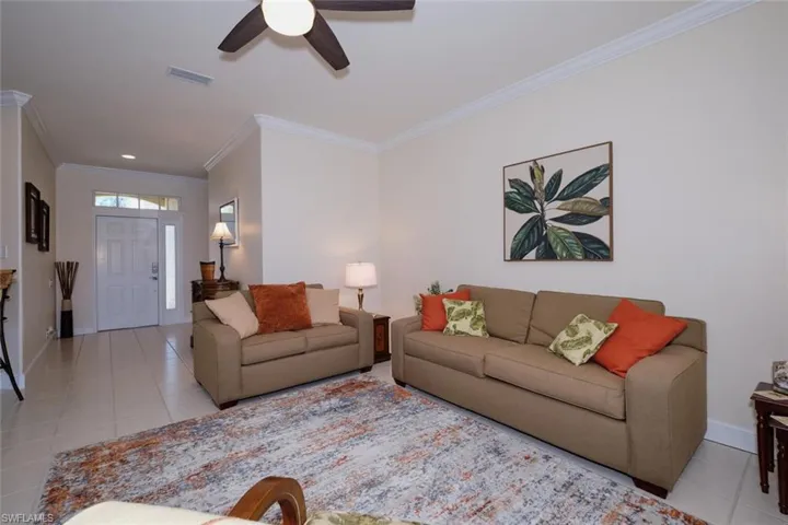 Living area with light tile patterned floors, a ceiling fan, and crown molding