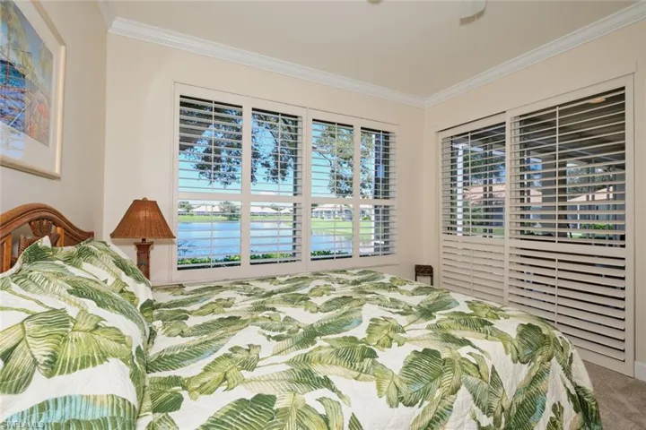 Bedroom with crown molding, a water view, carpet, and a ceiling fan