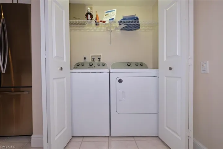Laundry area featuring light tile patterned flooring and washing machine and dryer