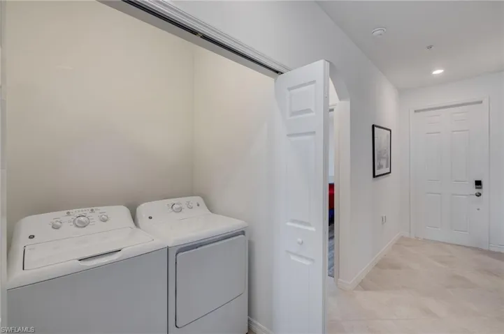 Laundry area with washer and clothes dryer, arched walkways, and recessed lighting