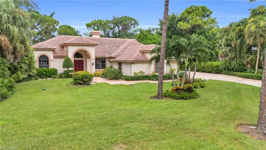 Mediterranean-style home with tile roof and palm trees