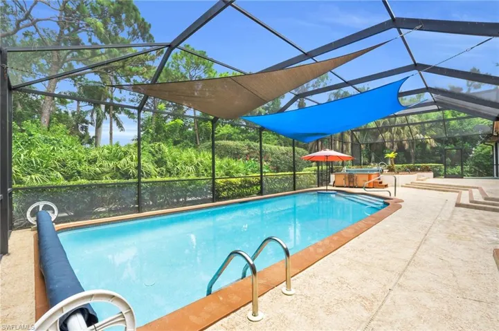 View of pool featuring a patio, a hot tub, and a lanai