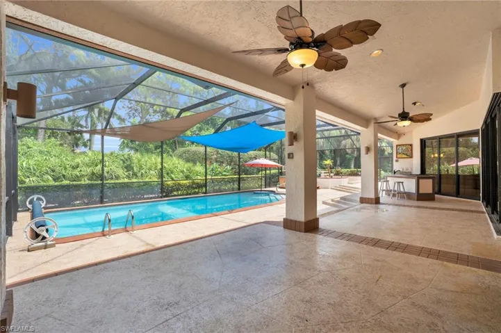 Pool area with lanai, ceiling fan, and tropical views