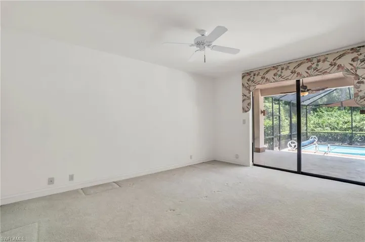 Carpeted Ensuite Guest Bedroom 1 with ceiling fan and sliding door to lanai