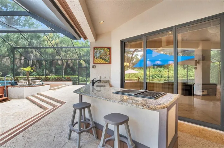 View of patio / terrace featuring an outdoor bar, glass enclosure, and exterior kitchen