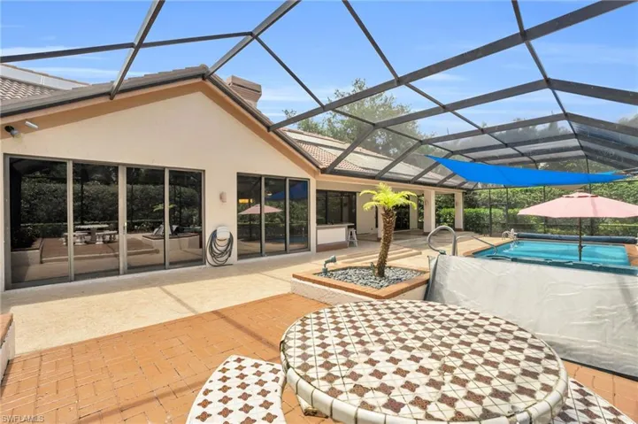 Expansive pool area with sunshade, outdoor seating, and lanai access