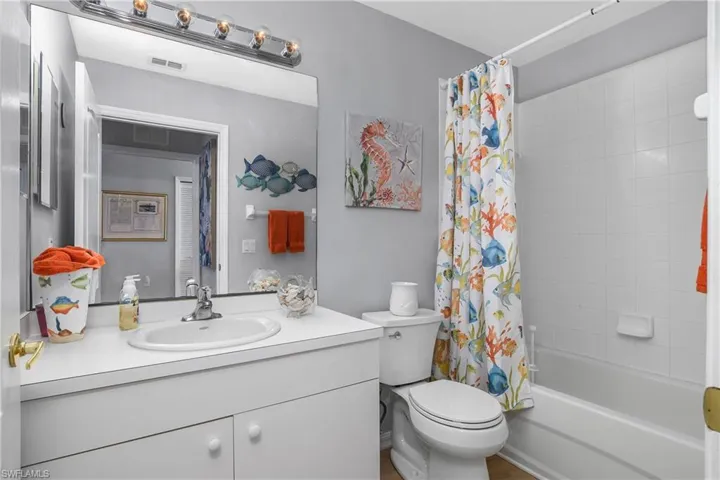 Full bath with toilet, shower / bathtub combination with curtain, visible vents, and vanity
