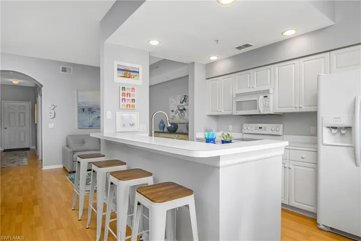 Kitchen with light countertops, white appliances, visible vents, and white cabinets