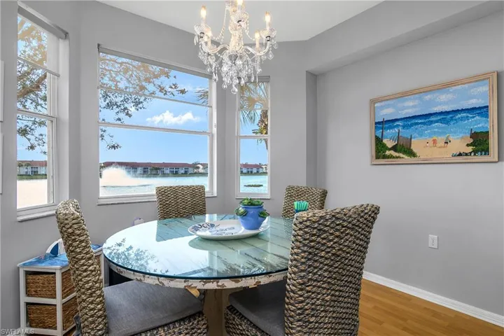 Dining area featuring a water view, a notable chandelier, baseboards, and wood finished floors