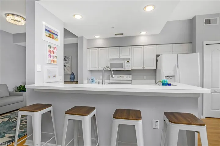 Kitchen featuring white cabinets, white appliances, visible vents, and light countertops