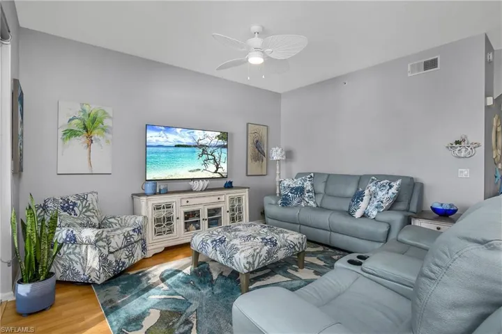 Living room featuring visible vents, ceiling fan, and wood finished floors