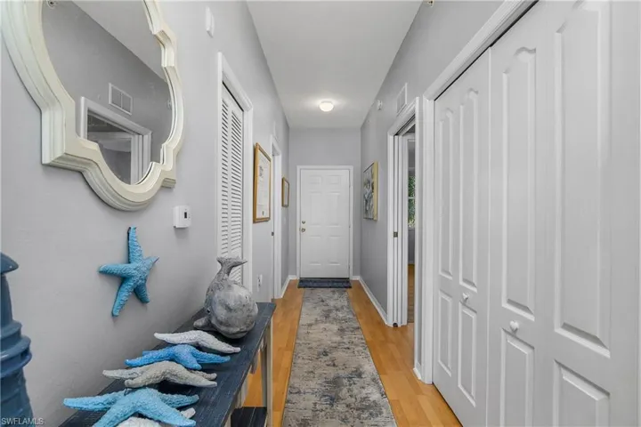 Corridor with visible vents, baseboards, and wood finished floors