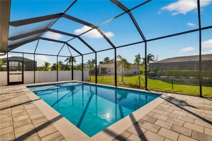 Swimming pool featuring a sunroom, glass enclosure, and a patio area