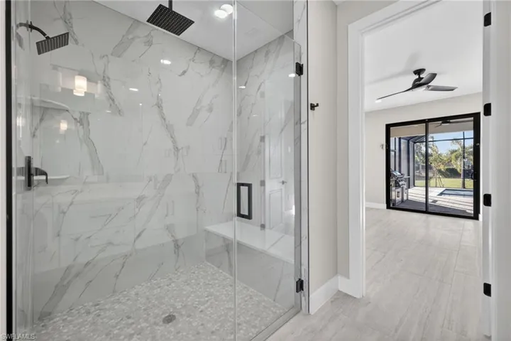 Bathroom featuring a marble finish shower and ceiling fan