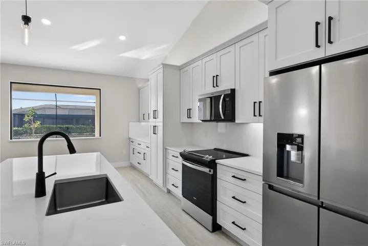Kitchen featuring appliances with stainless steel finishes, hanging light fixtures, white cabinets, light stone countertops, and recessed lighting