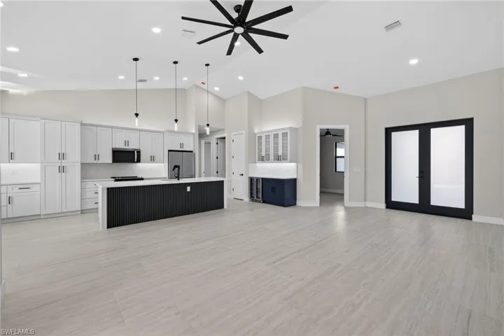Unfurnished living room featuring ceiling fan, high vaulted ceiling, recessed lighting, and french doors